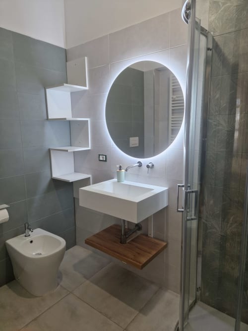 Bagno moderno all'Il 900 B&B di Avezzano con specchio rotondo illuminato, lavabo bianco e box doccia