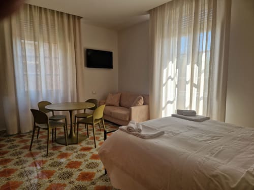 Camera moderna all'Il 900 B&B di Avezzano: letto, zona living, TV e vista sul giardino attraverso tende trasparenti