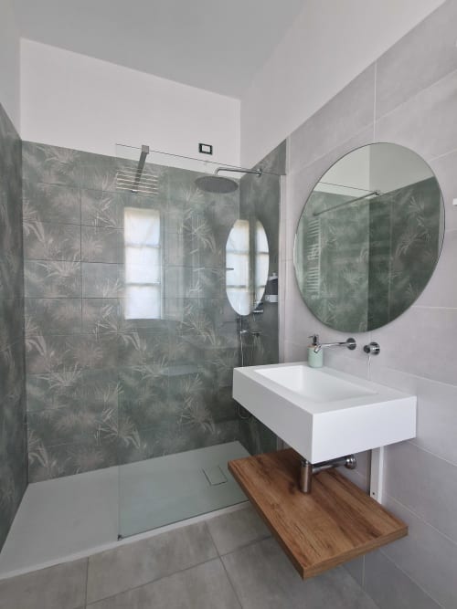 Bagno moderno all'Il 900 Avezzano con doccia a pioggia, specchio rotondo, lavabo bianco e piattaforma in legno
