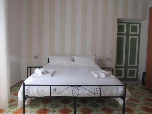 Camera da letto moderna con letto in ferro, carta da parati a righe e armadio verde presso l'Il 900 B&B di Avezzano