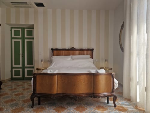 Elegante camera da letto presso l'Il 900 B&B ad Avezzano con letto in legno ornato, pareti rigate, porte verdi e vista sulla città