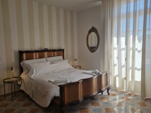 Camera da letto elegante con letto in legno, carta da parati a righe e vista sulla città presso Il 900 B&B ad Avezzano