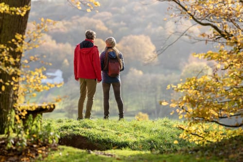Deux randonneurs avec sacs à dos admirant les paysages automnaux de la vallée près d'Aux 4 Chalets Corbion à Bouillon, Belgique