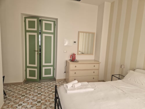 Camera da letto all'Il 900 BnB di Avezzano con letti gemelli, porte verdi, cassettone e carta da parati a righe