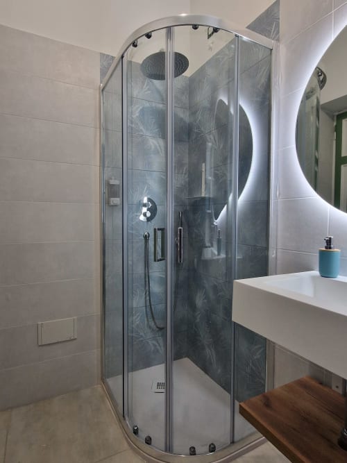 Moderna cabina doccia a Il 900 Avezzano con piastrelle scure decorate e specchio illuminato a LED
