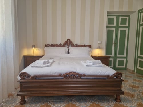 Letto in legno decorato con biancheria bianca in Camera Avventura presso l'Il 900 B&B ad Avezzano, Italia