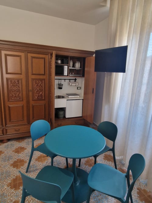 Tavolo da pranzo turchese con sedie nella camera Avventura dell'Il 900 B&B di Avezzano, con angolo cottura e guardaroba