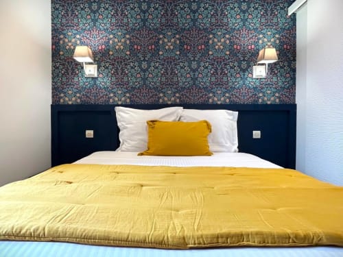Chambre douillette aux Maisons Delphine Le Cottage avec literie jaune, tête de lit marine et papier peint à motifs ornementaux