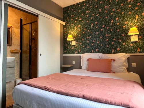 Chambre double supérieure Maisons Delphine avec papier peint floral, literie rose, appliques murales et salle de bain attenante