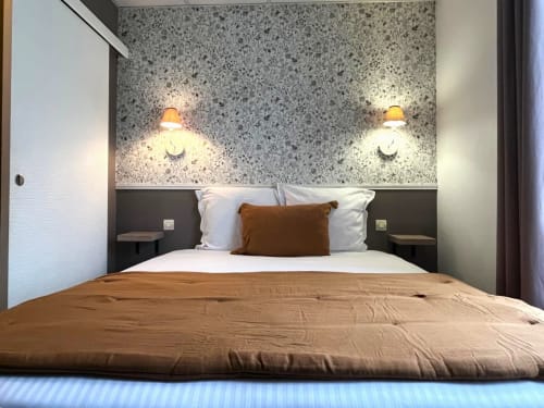 Chambre double supérieure à Maisons Delphine Le Cottage avec mur d'accent en terrazzo, éclairage ambiant et literie marron