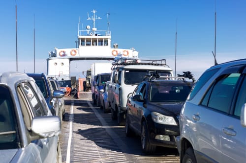 Cars parked on ferry deck with blue and white vessel at Lion sur Mer, France