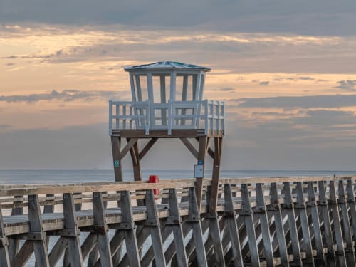 Elevated lifeguard tower with blue railings overlooking the beach at Lion sur Mer, France during sunset