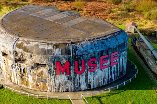 Aerial view of Musée bunker at Hotel De Lion Sur Mer in Normandy with deteriorated concrete structure and red lettering