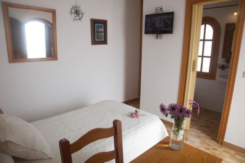 Habitación individual en Hostal Mar de Frente con cama, muebles de madera, flores, TV y acceso en Los Caños de Meca