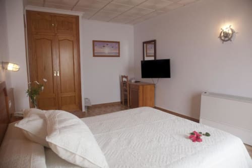 Dormitorio doble moderno en Hostal Mar de Frente con TV, ropa de cama blanca, armario de madera y decoración náutica en Los Caños de