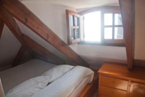 Acogedora habitación doble en Hostal Mar de Frente con vigas de madera, ventana con vista al mar y mobiliario de madera