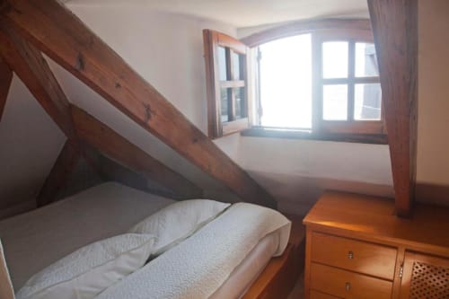 Habitación doble en desván del Hostal Mar de Frente con vigas de madera, ropa de cama blanca y vistas a Los Caños de Meca