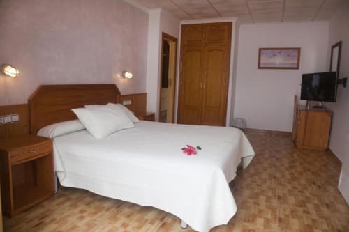 Amplio dormitorio doble en Hostal Mar de Frente, Los Caños de Meca, con muebles de madera, TV y terraza con vistas al mar