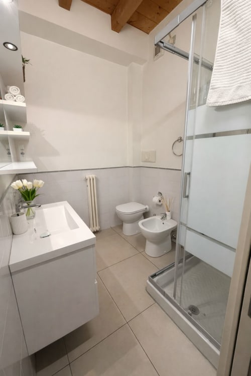 Bagno moderno nella Lilia Luxury Suite a Bergamo con lavabo bianco, wc, bidet e doccia in vetro