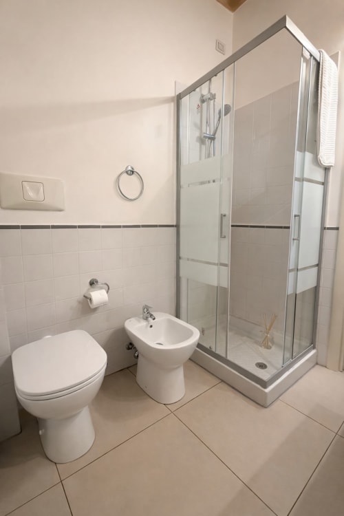 Bagno moderno della Lilia Luxury Suite a Bergamo con wc, bidet, box doccia in vetro e piastrelle bianche