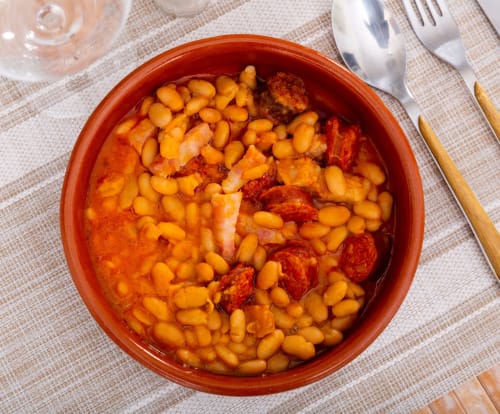 Spanish beans and chorizo stew served in red ceramic bowl at Posada La Colodra, Los Tojos