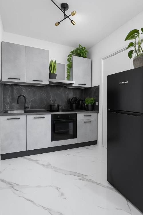 Cucina moderna in bianco e nero nella Lilia Luxury Suite Bergamo con pavimento in marmo, alzatina scura e piante in vaso
