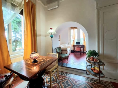 Élégante salle à manger du Palazzo Losio avec table en bois, portail voûté, carrelage en terre cuite et rideaux dorés