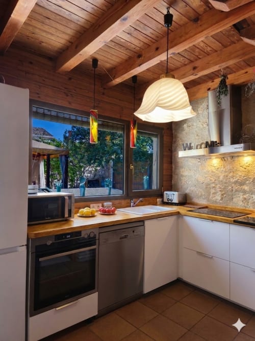 Cuisine contemporaine aux poutres bois, mobilier blanc et accents pierre de la maison Viento de Ladera à Ségovie