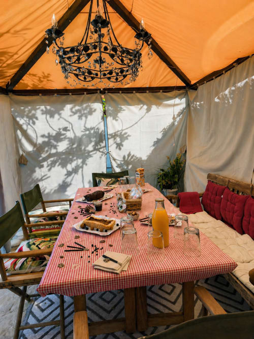 Configuration élégante de salle à manger en extérieur sous tente à la maison Viento de Ladera à Ségovie avec lustre, nappe à carreaux rouges et