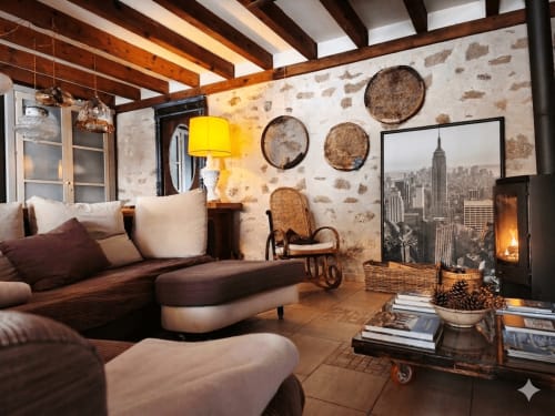 Salon chaleureux du gîte Viento de Ladera à Ségovie avec cheminée, canapé marron, paniers décoratifs et vue sur la ville