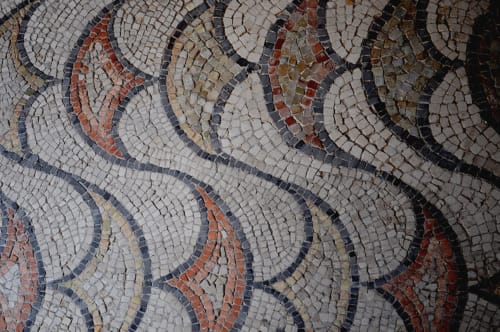 Intricate mosaic floor with geometric patterns in white, navy, red, and tan tiles at Cristallo Apartment in Ravenna