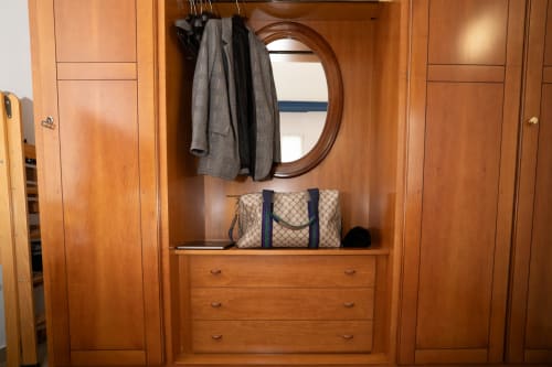 Guardaroba in legno dell'appartamento Tramonto presso Match Home con specchio rotondo, stendibiancheria, borsa fantasia e cassetti portaoggetti