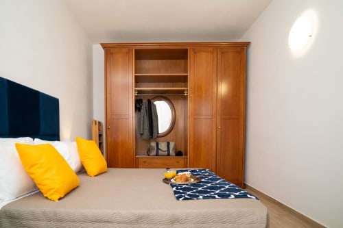 Camera luminosa a Match Home Somma Lombardo con armadio in legno, cuscini gialli e accenti blu navy