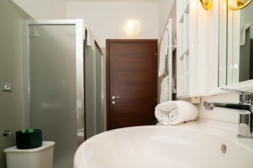Bagno moderno nell'APT Tramonto di Match Home a Somma Lombardo, con lavabo bianco, specchio e porta in legno scuro
