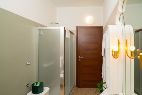Bagno moderno dell'appartamento Match Home a Somma Lombardo con doccia in vetro, porta in legno e applique in ottone
