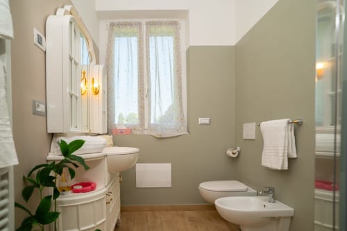 Bagno moderno in appartamento a Somma Lombardo con pareti verde salvia, sanitari bianchi, wc, bidet, lavabo, specchio, portasciugamani