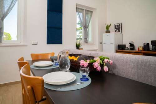 Moderna zona pranzo con sedie arancioni, tulipani rosa e divano grigio nell'appartamento Tramonto presso Match Home, Somma Lombardo