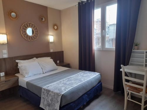 Chambre double à l'Hôtel le Vauban à Carentan avec lit en bois, miroirs décoratifs, rideaux bleus et équipements modernes
