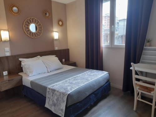 Chambre avec lit double à l'Hôtel le Vauban à Carentan, miroirs décoratifs, rideaux épais et mobilier en bois