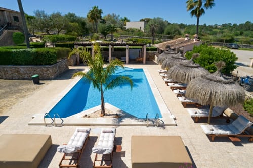 Piscina del resort Agroturismo Ses Illes en Costitx con tumbonas, sombrillas palapa y jardines exuberantes