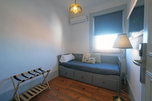 Quarto aconchegante em albergue em Santiago de Caminha com cama cinza, piso de madeira, luminária pendente e vista para o jardim