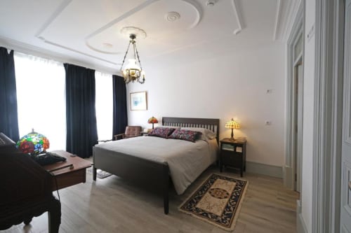 Quarto elegante na Pousada Boutique Santiago de Caminha com cama de madeira escura, vista da cidade, luminárias decorativas e acabamento branco moderno