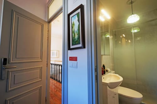 Casa de banho moderna no albergue de Caminha com lavatório, espelho, sanita e box de duche
