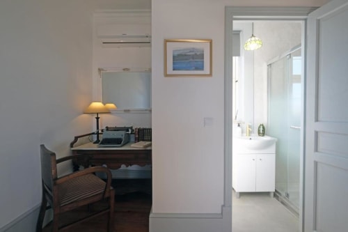 Quarto 203 da Pousada Boutique Santiago de Caminha com escrivaninha, máquina de escrever, luminária e entrada para banheiro moderno