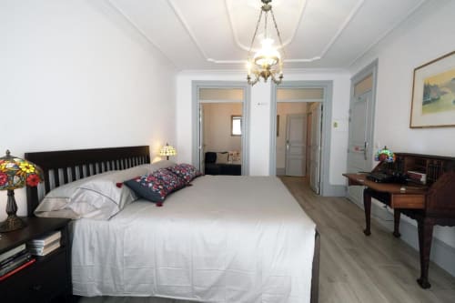 Quarto espaçoso na Santiago de Caminha Boutique Hostel com cama queen, cabeceira escura, escrivaninha, luminária de vitral e vista da cidade