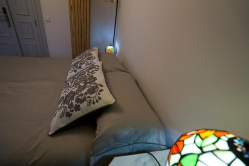 Quarto aconchegante da Pousada Boutique Santiago de Caminha com almofada decorativa, luminárias coloridas e vista para o jardim em Caminha