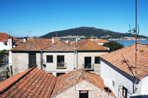 Edifícios históricos com telhados de terracota em Caminha, com vistas do rio em direção à encosta florestada, Santiago de Caminha Boutique