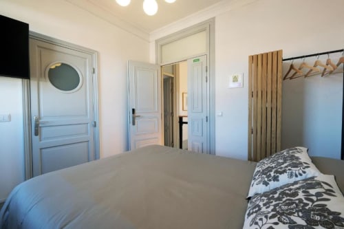 Quarto moderno no Santiago de Caminha Boutique Hostel com cama, portas azuis, guarda-roupa de madeira e piso de madeira em Caminha.
