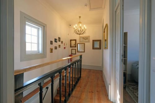 Elegante corredor com escadaria de madeira, lustre e espelhos emoldurados no Santiago de Caminha Boutique Hostel em Caminha,