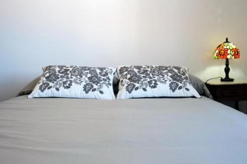 Quarto no Santiago de Caminha Boutique Hostel com cama queen, almofadas decorativas, luminária Tiffany na cabeceira e vista para o jardim